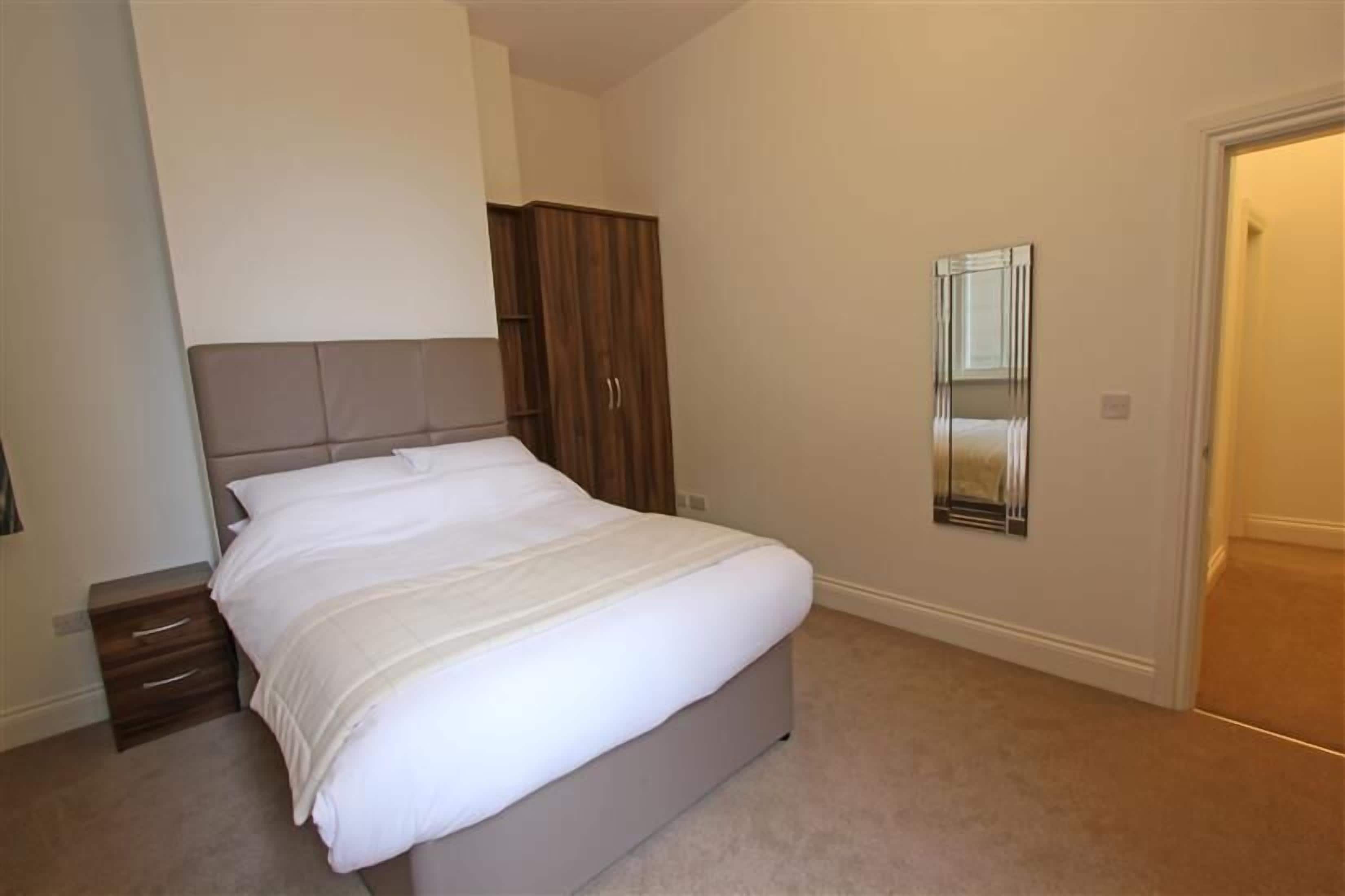Ein Schlafzimmer mit Bett, Kleiderschrank, Spiegel und Tür.