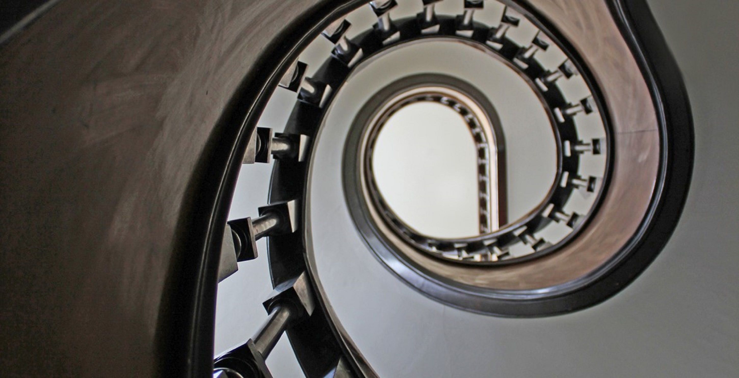 Eine Wendeltreppe mit metallischer Oberfläche und einem runden Fenster im Zentrum.