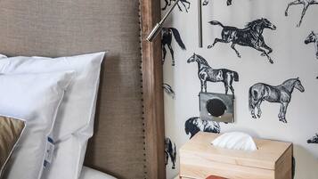 Ein ordentlich gemachtes Bett mit Kissen, ein Nachttisch mit Lampe, Radio und Büchern.