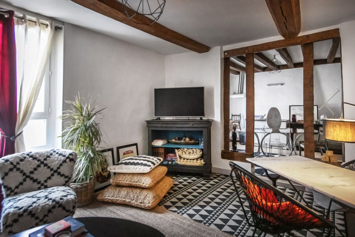 Un salon comprenant un canapé, un téléviseur, une cheminée et un coin repas avec une table et des chaises.