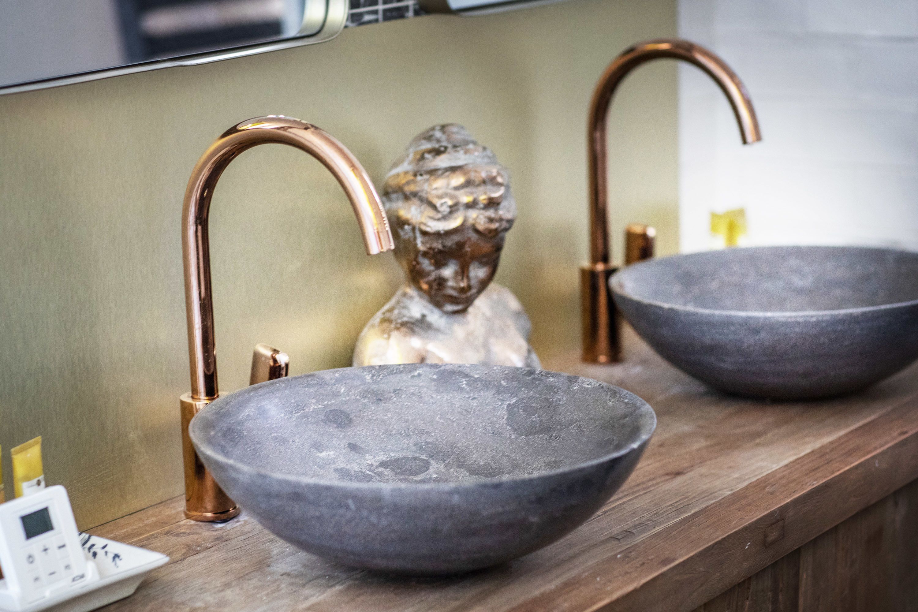 A bathroom with two stone sinks, copper faucets, and a scale.