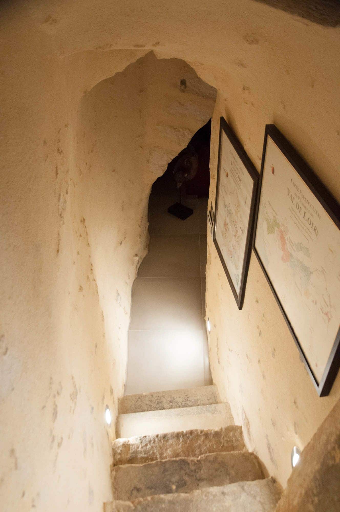 A narrow, arched stone staircase leading downwards, with a light source at the top.