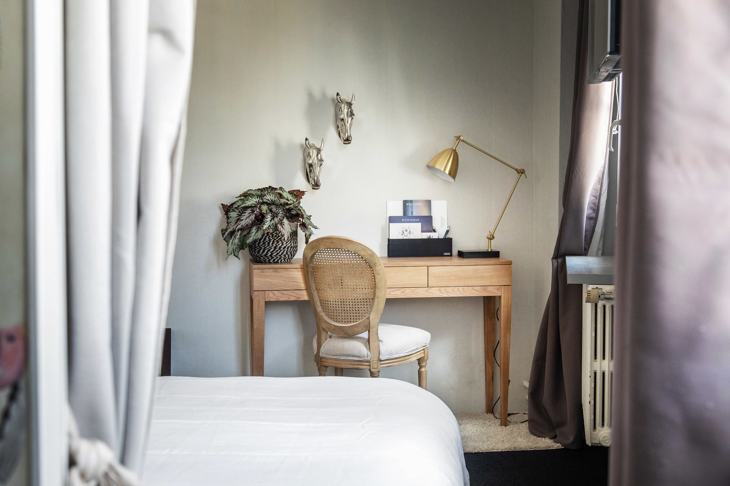 Quarto com cama, escrivaninha, cadeira, luminária e objetos decorativos.