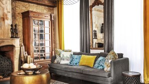 Un salón con un sofá gris, cojines estampados, un aparador de madera y una mesa de centro redonda.