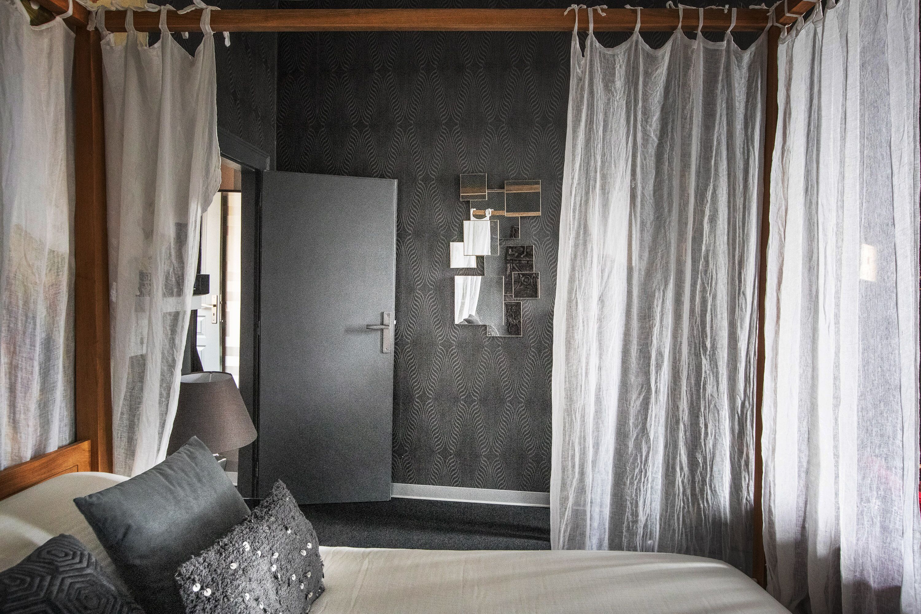 Un dormitorio con cama, almohadas, mesita de noche, lámpara y armario.