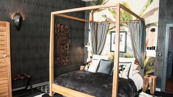 Un lit à baldaquin avec une couvre-lit sombre et texturée, une tête de lit en bois et des rideaux gris.