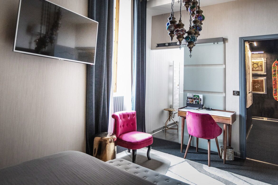 Ein modernes Schlafzimmer mit einem Bett, einem Schreibtisch, zwei Stühlen, einem Spiegel und einer Chandelier.