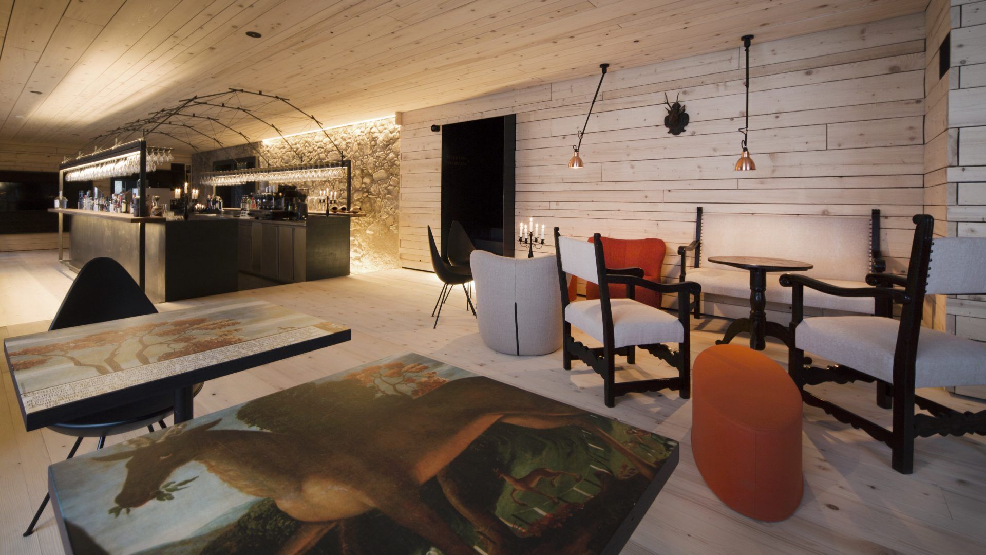 A cozy interior with a bar area, wooden walls, and a mix of modern and classic furniture.