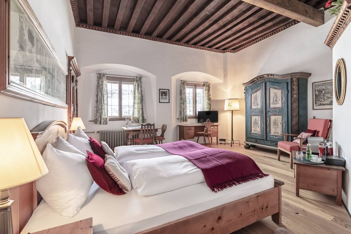 A bedroom with a wooden bed, a desk, a chair, and a wardrobe.