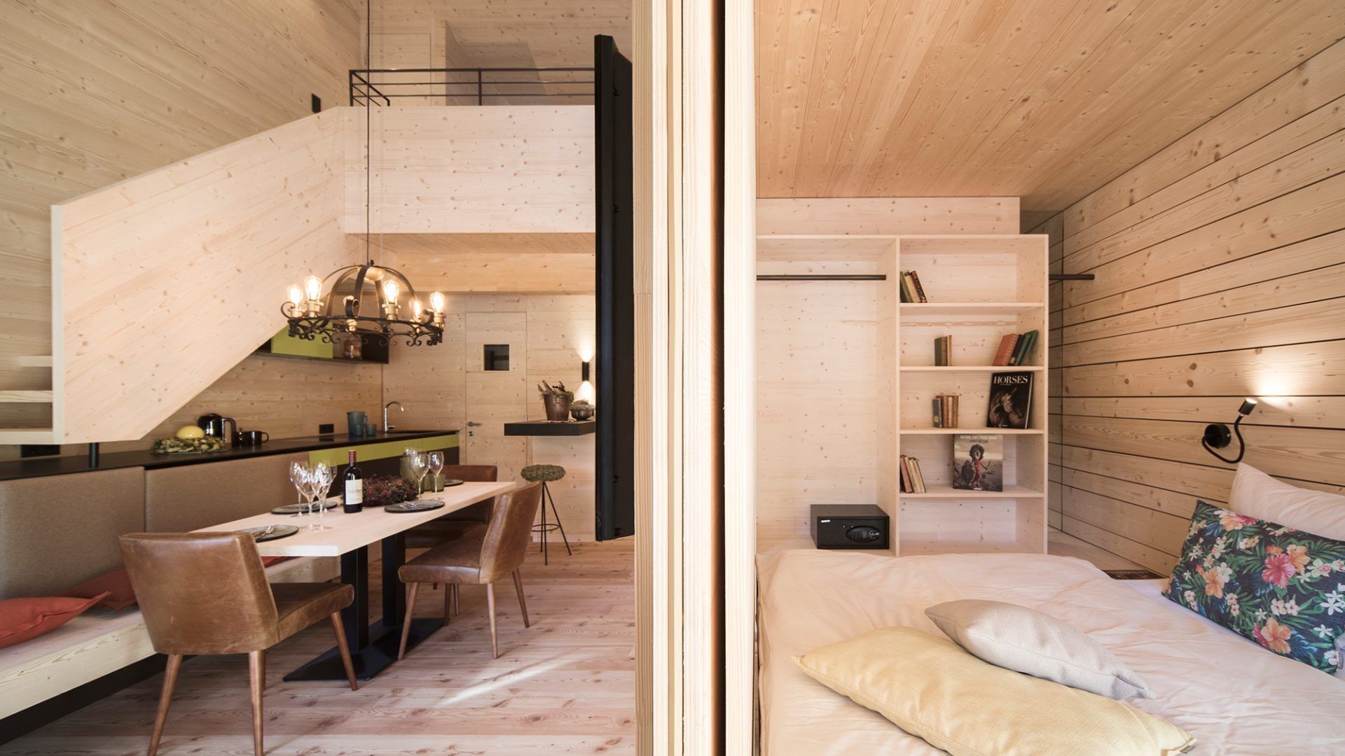 A compact, modern room with a dining area, a bed, and a built-in bookshelf.