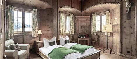 A wooden-paneled bedroom with a bed, a chair, a nightstand, and a lamp.