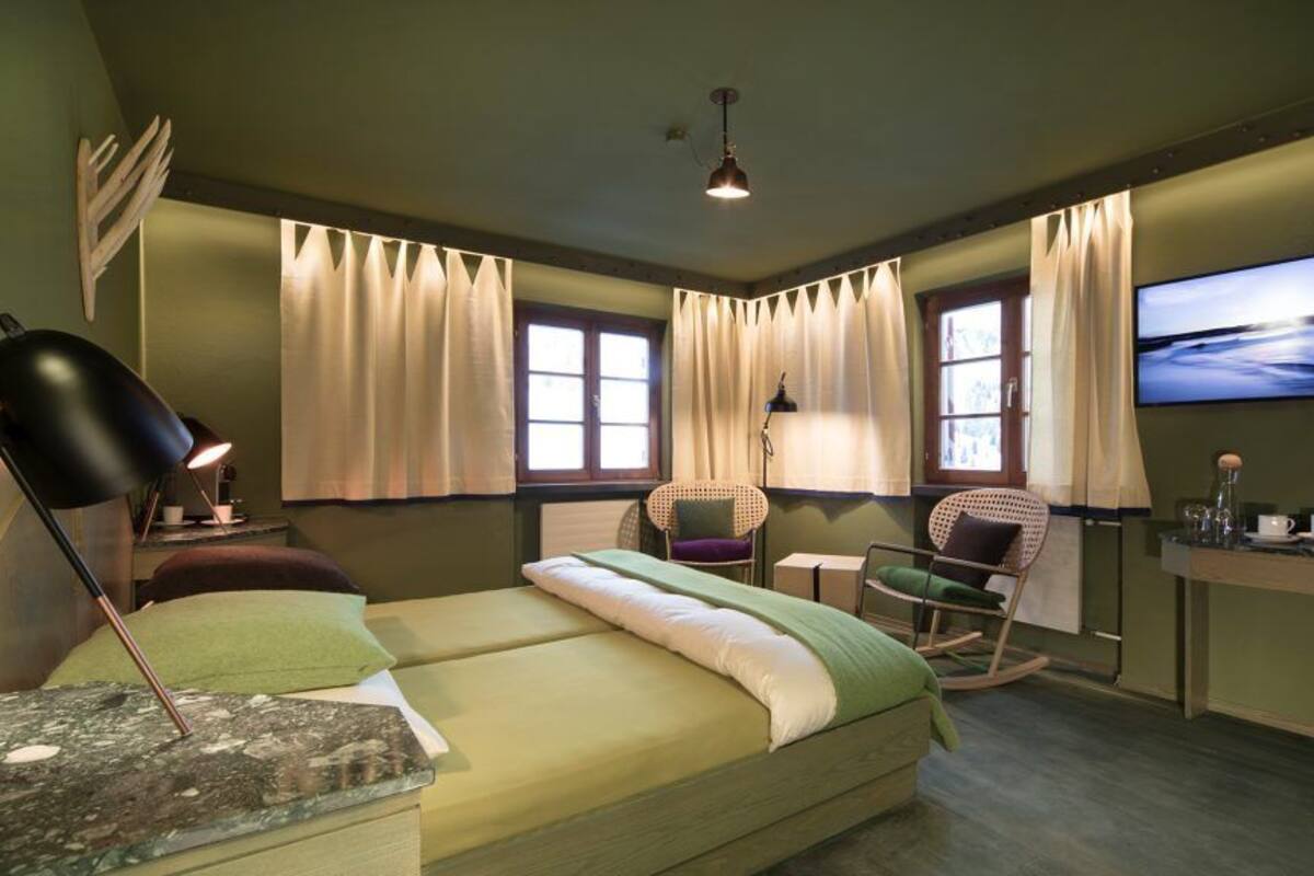 A bedroom with a bed, a desk, a chair, a lamp, and a TV.