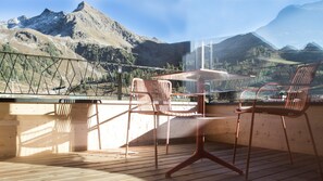 A wooden deck with a table and chairs, overlooking a mountainous landscape. - Hotel Jagdschloss Resort (Silz)