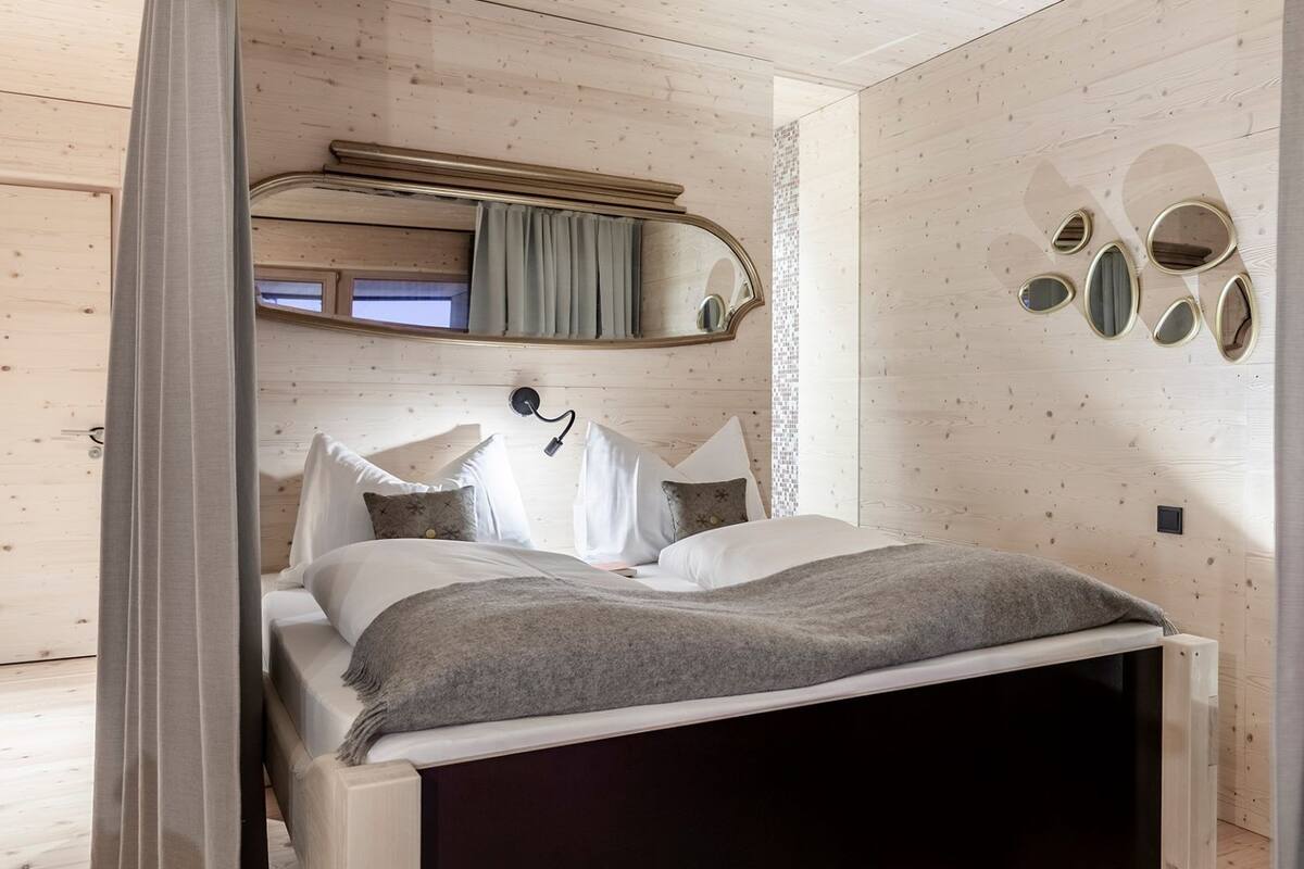 A bedroom with a bed, a mirror, and a wall with decorative elements.