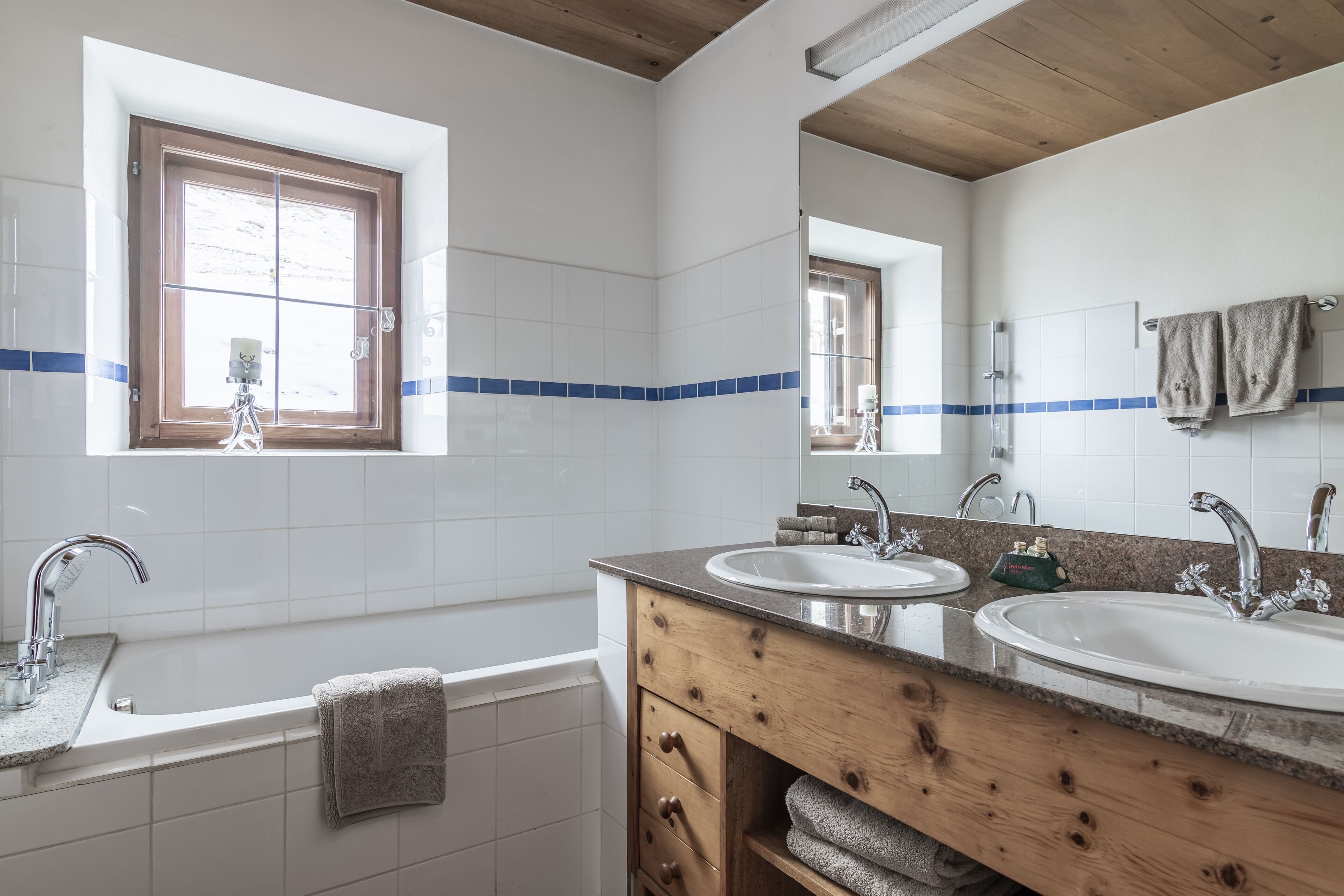 Baño con dos lavamanos, una ventana y un mueble de tocador de madera.