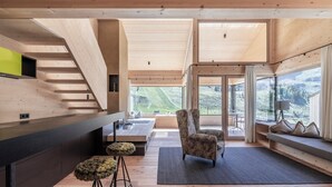 Een modern interieur met een houten trap, een keukenhoek, een zithoek met uitzicht en een groot raam.