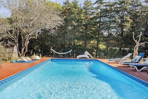 Una piscina rectangular con agua azul cristalina, rodeada por una terraza de madera.