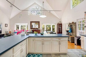 A spacious kitchen with a large island, white cabinetry, and a dining area with a view.