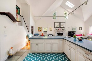 A spacious kitchen with a large island, white cabinetry, and a dining area with a sofa and table.