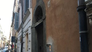 A narrow street with buildings on either side, a metal firebox on the wall, and a parked car. - Chroma Apt Farinone 28 (Rome)