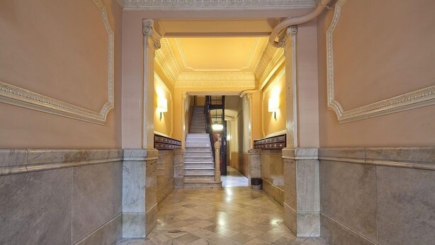 Um corredor com piso de mármore e escada que leva a um patamar.