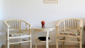 Two wooden chairs with a small round table between them, a vase with flowers, and framed pictures on the wall. - 2BDR Amazing Location with Parking (Tel Aviv)