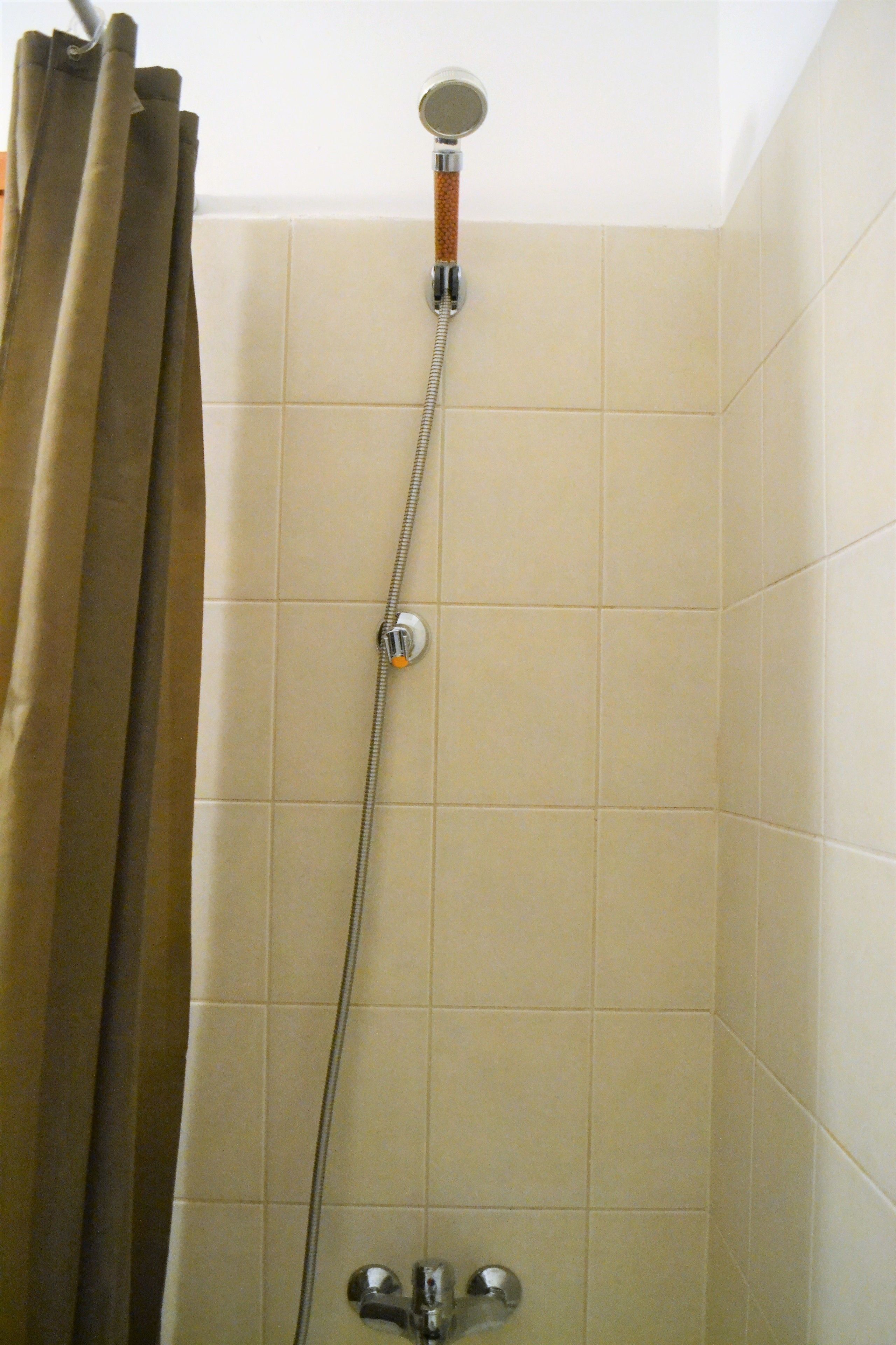 A shower with a handheld showerhead and a control knob.