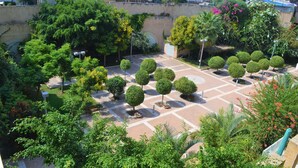 A courtyard with neatly trimmed trees, a paved walkway, and a bench. - 2BDR Amazing Location with Parking (Tel Aviv)