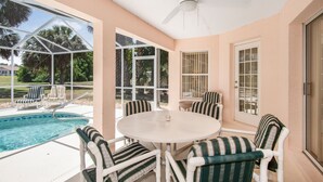 A covered outdoor area with a pool, chairs, and a table. - Villa Valk - Comfort - 3 Bedroom (Hernando)