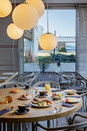 A round dining table with chairs, a variety of dishes, and a view of the outdoors. - Blue Orange Resort (Prague)