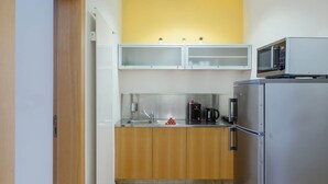 Cocina compacta con microondas, refrigerador y armarios de madera.