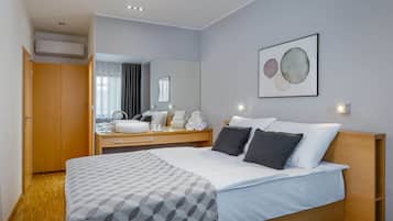A hotel room with a bed, bedside table, mirror, and a wall-mounted artwork.