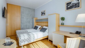 Un dormitorio con cama, escritorio, silla y televisor.