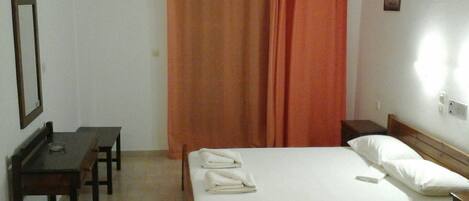A small, clean room with a bed, a desk, and a chair.