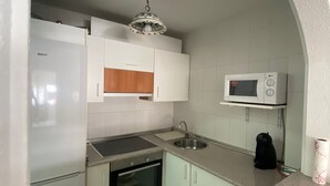 A compact kitchen with white cabinets, a built-in oven, a microwave, and a sink. - Apartment in Laguna Beach 1st Line Beach with WIFI (Torrox)