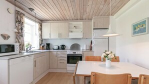 Une cuisine moderne dotée de meubles en bois, d’un four à micro-ondes, d’une machine à café et d’un coin repas avec une table et des chaises.
