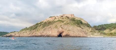 A coastal landscape with a prominent hill featuring a castle-like structure.