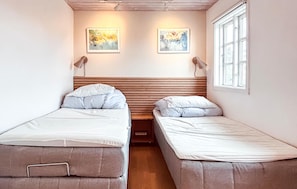 A small, cozy room with two single beds, a wooden headboard, a window with curtains, and two wall-mounted lamps. - 2 bedroom gorgeous apartment in Allinge (Allinge)