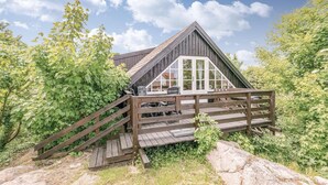 A wooden cabin with a sloped roof, a deck with a wooden staircase, and a large window. - 2 bedroom gorgeous apartment in Allinge (Allinge)