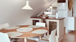 A modern kitchen with a wooden dining table, white chairs, and a white refrigerator. - 2 bedroom gorgeous apartment in Allinge (Allinge)