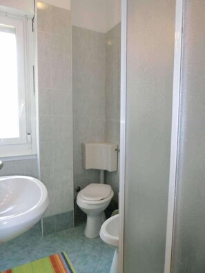 Et badeværelse med toilet, bidet og et vindue.