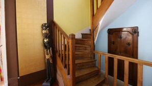 Una escalera de madera con barandilla, un armario de madera oscura y una estatua a la izquierda.