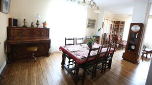 Un comedor con mesa y sillas de madera, un piano y una estantería al fondo.