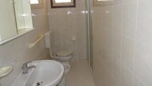 Une salle de bain avec un lavabo, des toilettes et une douche.