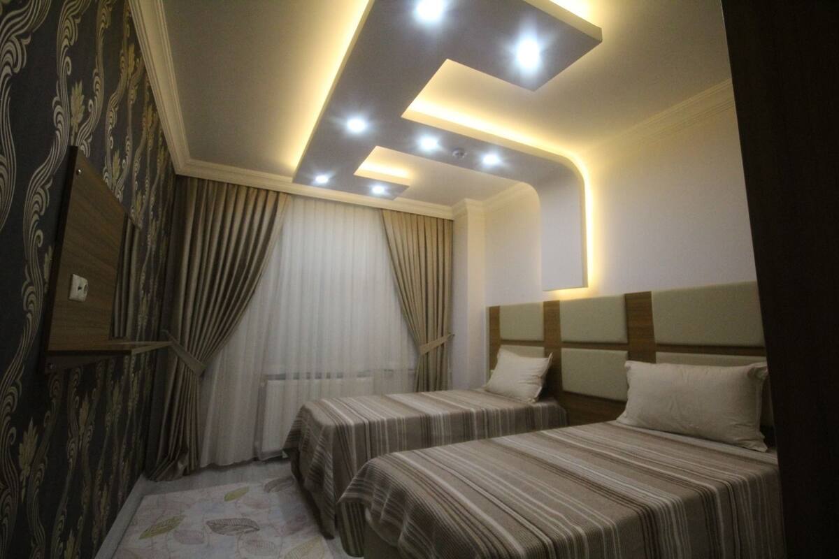 Ein Hotelzimmer mit zwei Betten, einem großen Spiegel und einer Deckenleuchte.