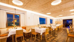 Un restaurant avec des murs lambrés, des nappes blanches et des chaises orange.