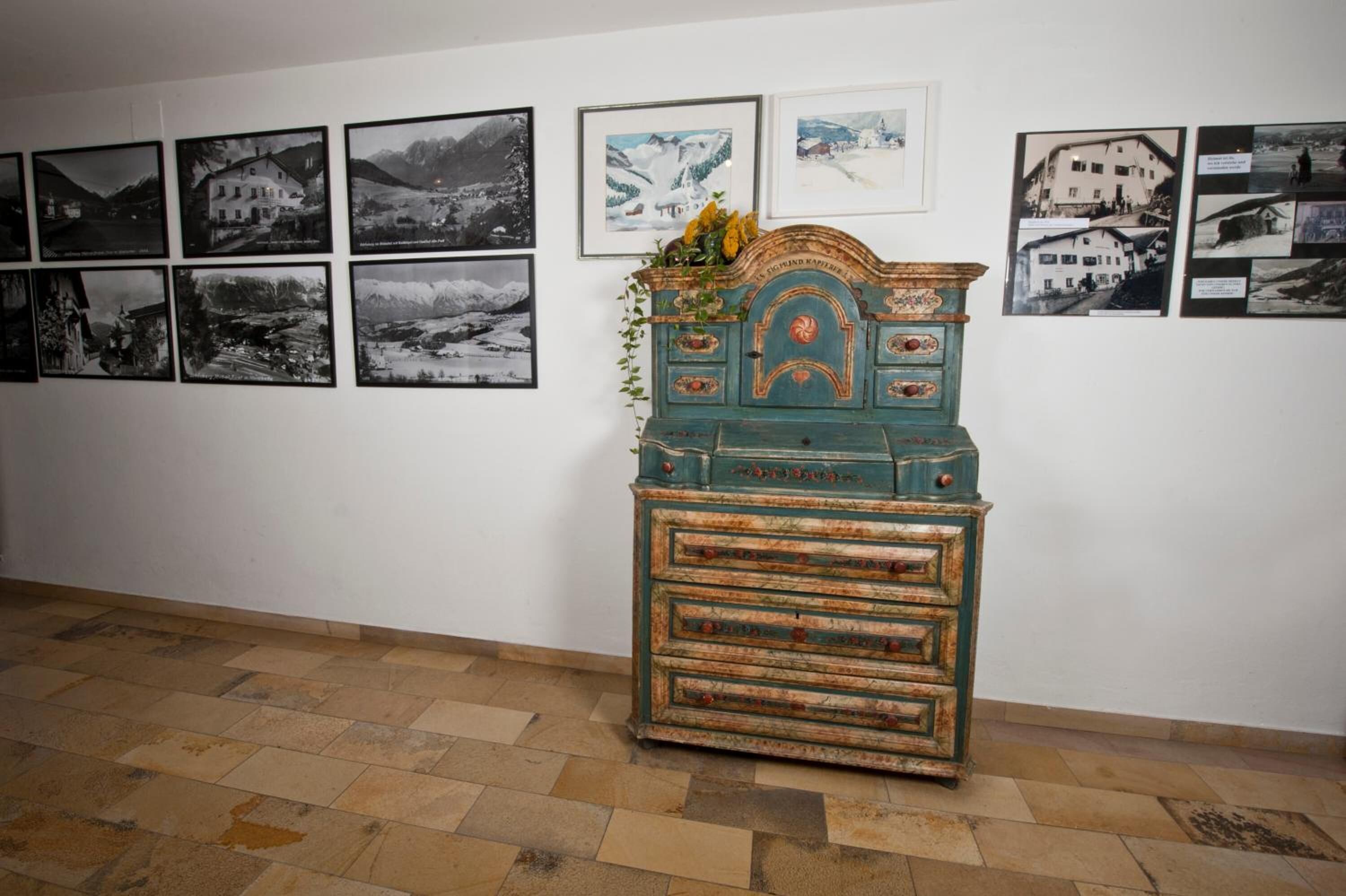 Une pièce avec une commode ancienne et un mur décoré de photographies en noir et blanc.
