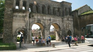 A historic stone archway with tourists gathered around. - Camping d'Autun (Autun)