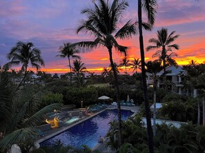 Ett semesterparadis med pool, palmer och utsikt över solnedgången.