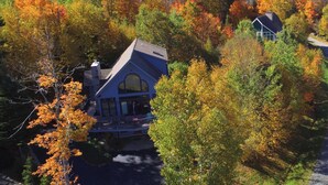 Une grande maison moderne, entourée d’un feuillage dense aux couleurs automnales.